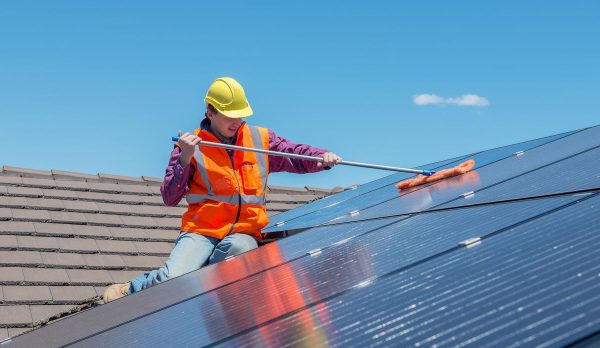 worker and solar panels young worker cleaning solar panels on house roof